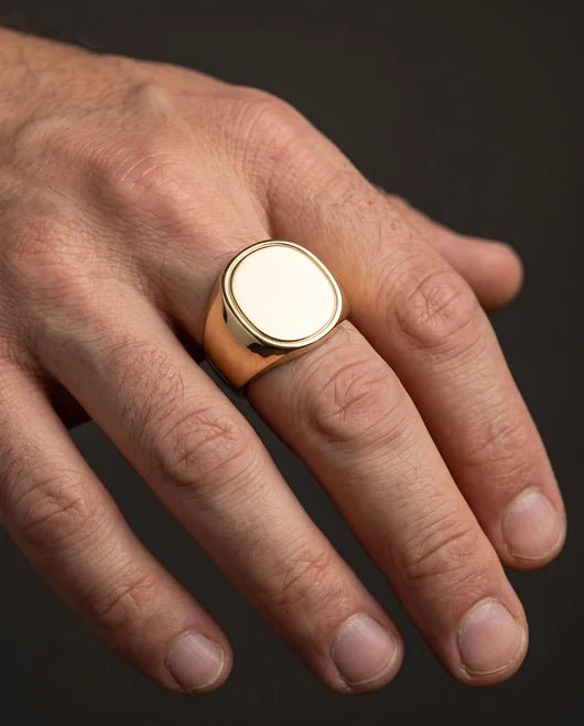 The finished low-profile yellow gold signet ring on a man's hand