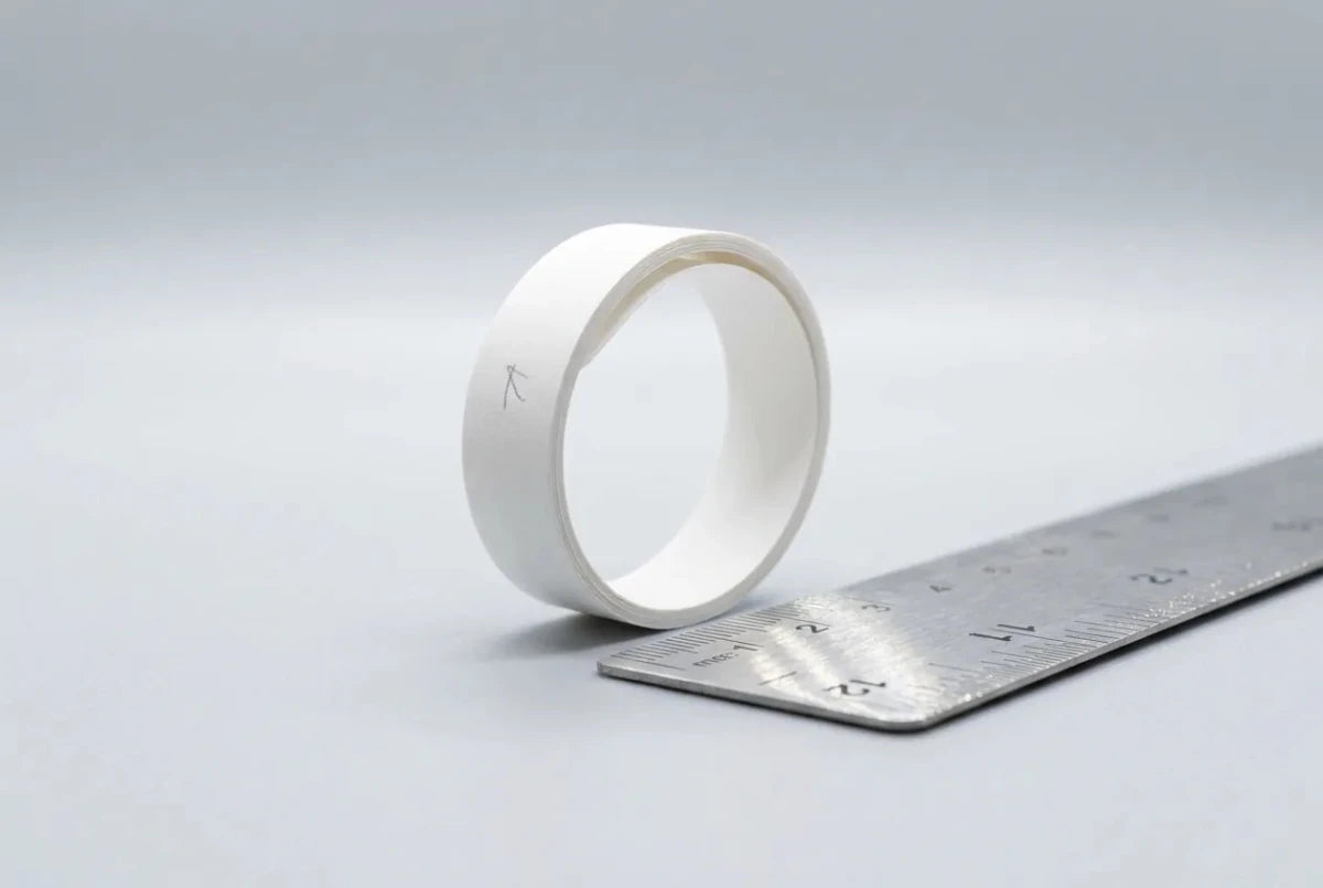 A narrow strip of paper wrapped around a finger next to a steel ruler