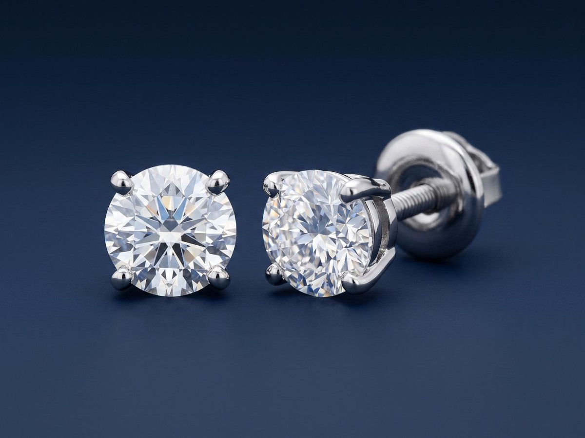 A pair of round diamond stud earrings in white gold on a deep navy studio ground