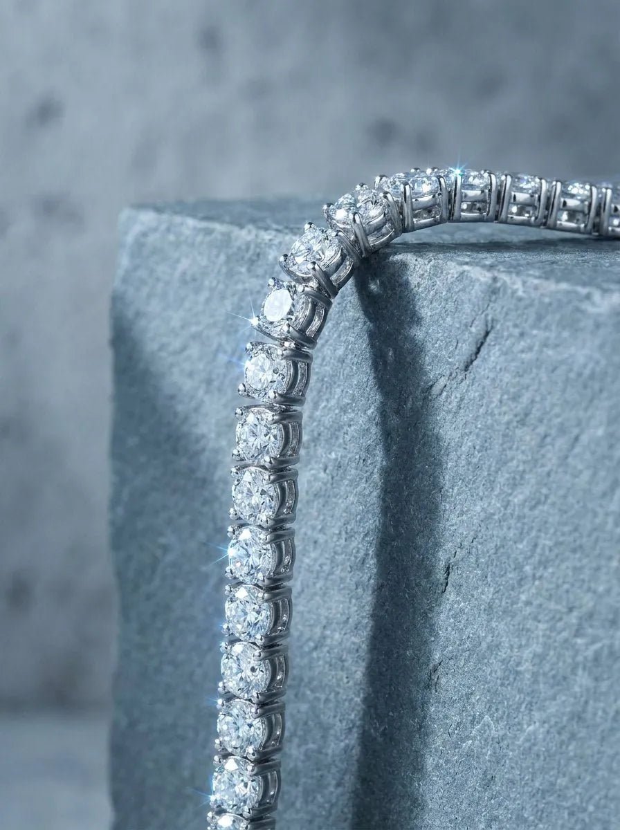 A diamond tennis bracelet draped over the edge of a gray stone block
