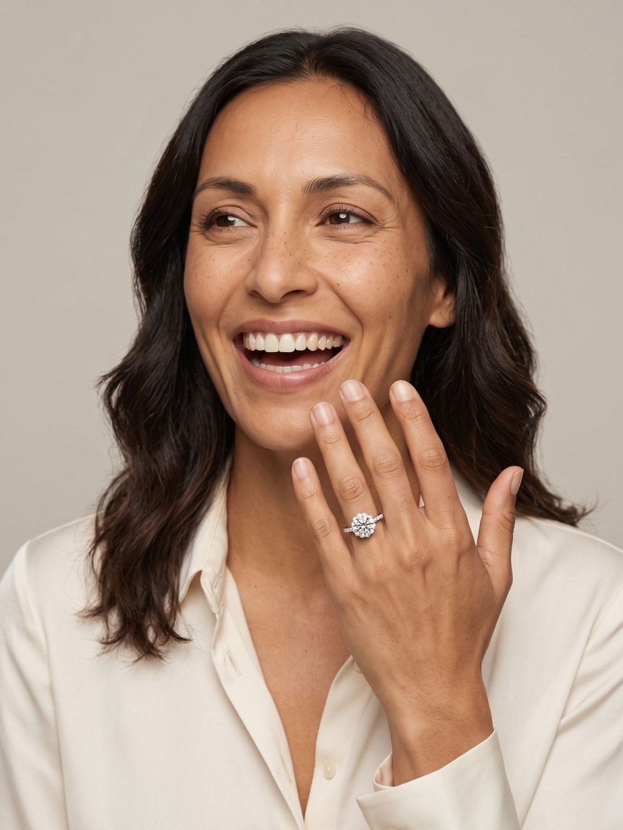 Model A in cream, hand at her collar, wearing a round diamond solitaire engagement ring