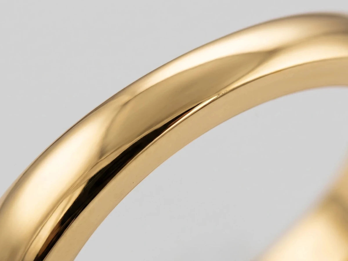 Macro close-up of a polished yellow gold ring shank filling the frame, showing the finish left by final polishing
