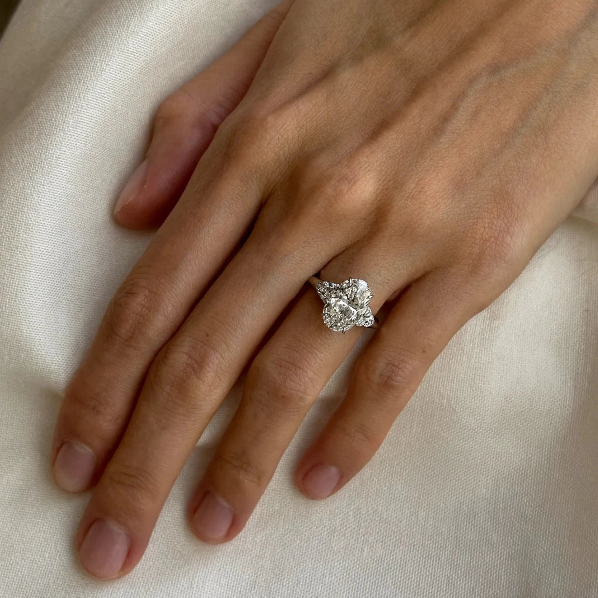 A hand wearing only an oval solitaire engagement ring