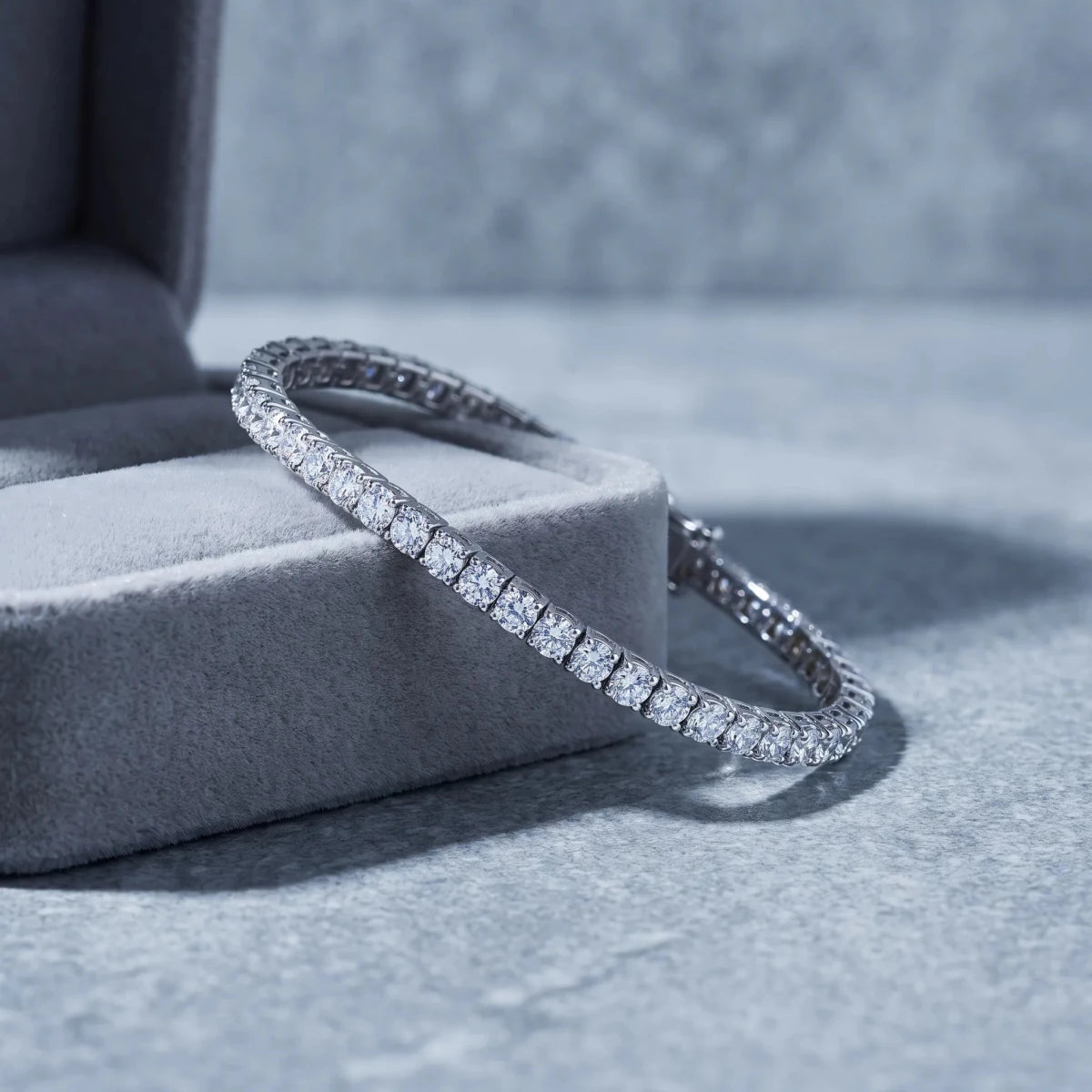 A diamond tennis bracelet draped over a velvet jewelry box