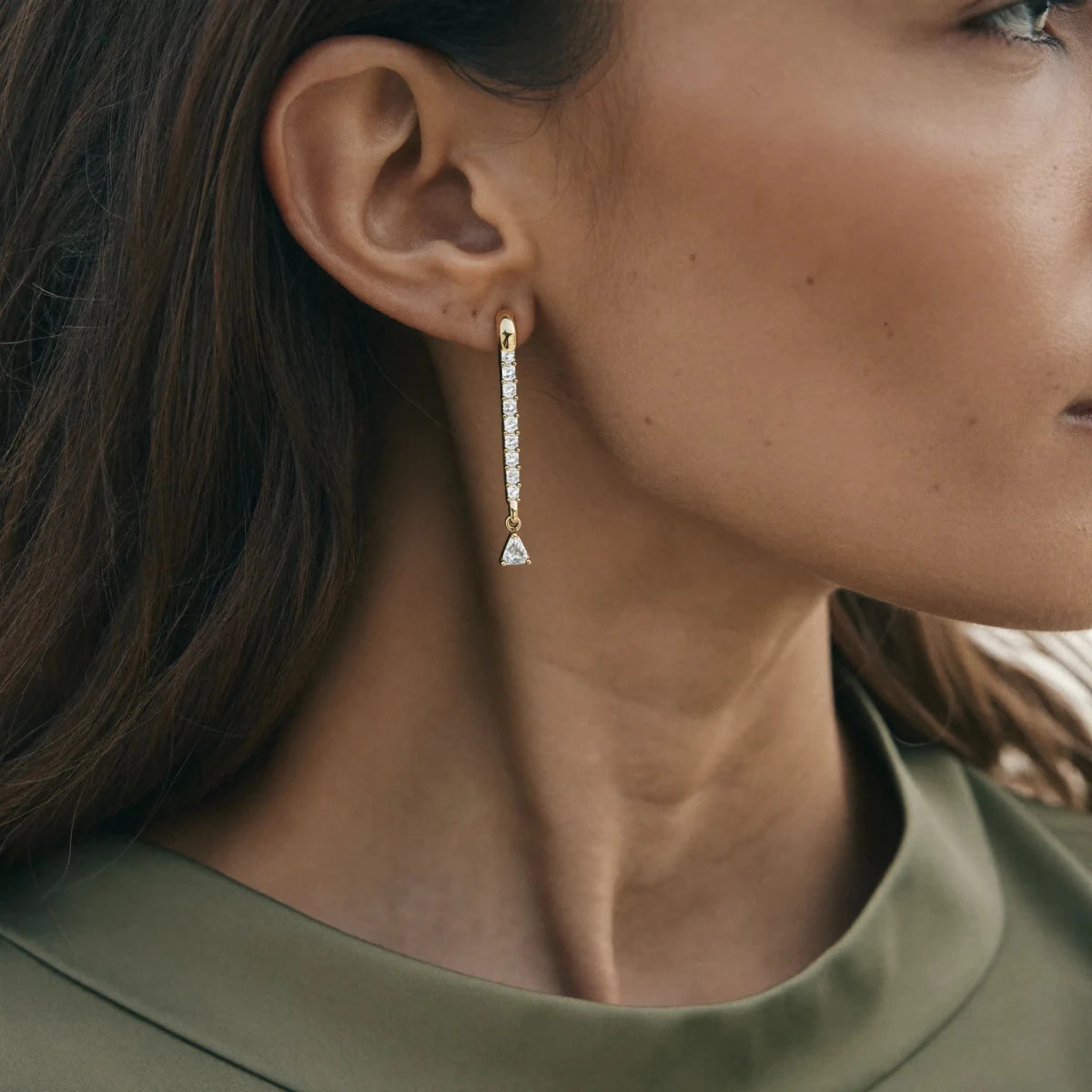 A profile view of an ear wearing a diamond drop earring