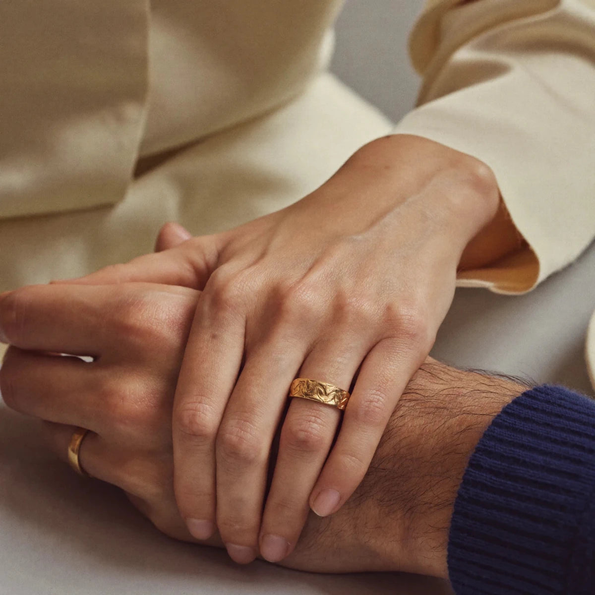 A couple holding hands, one wearing a simple gold band