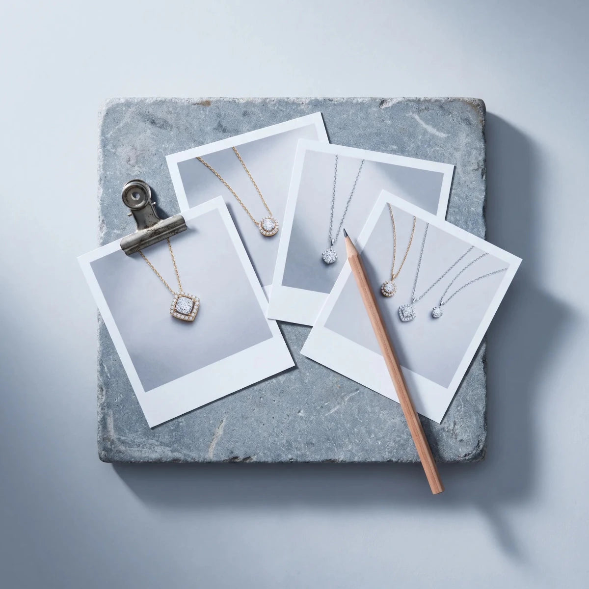 Printed photos of diamond pendants on a designer's desk