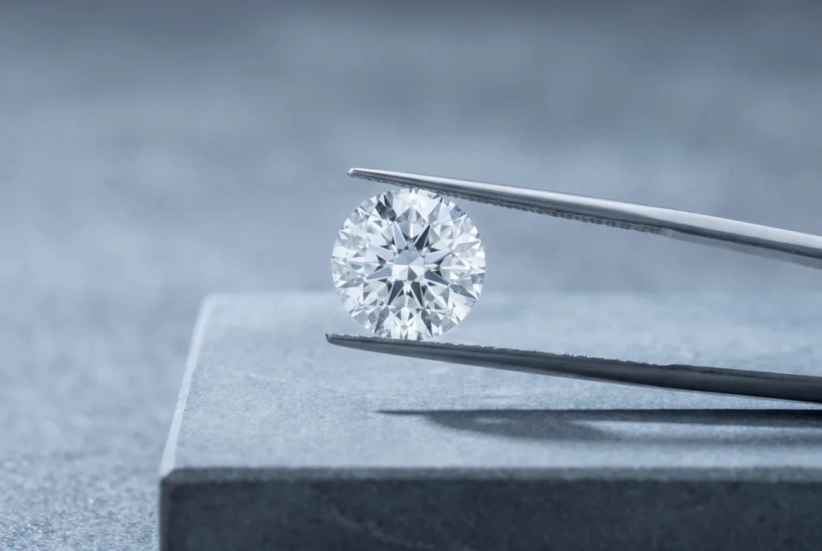 A round diamond gripped in steel tweezers and held close for examination