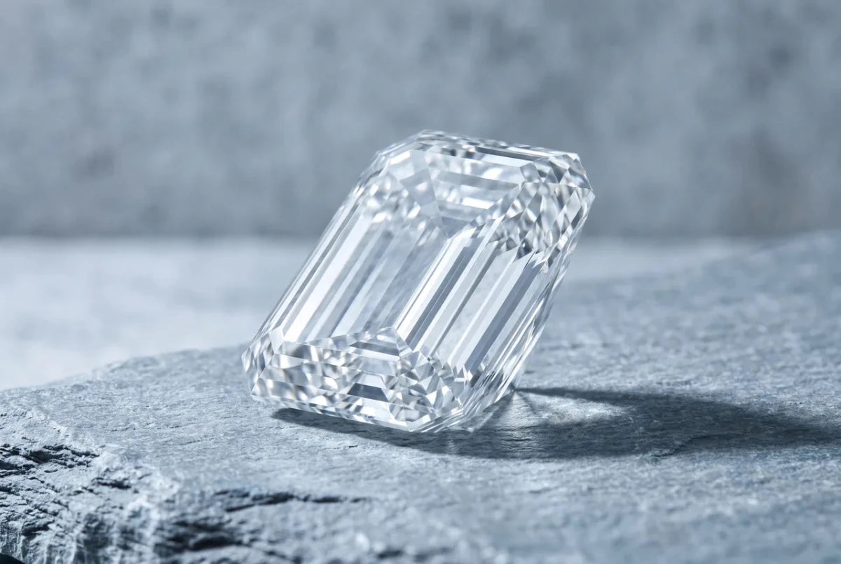 An emerald-cut diamond lying face-up, its long parallel step facets forming an open window into the stone