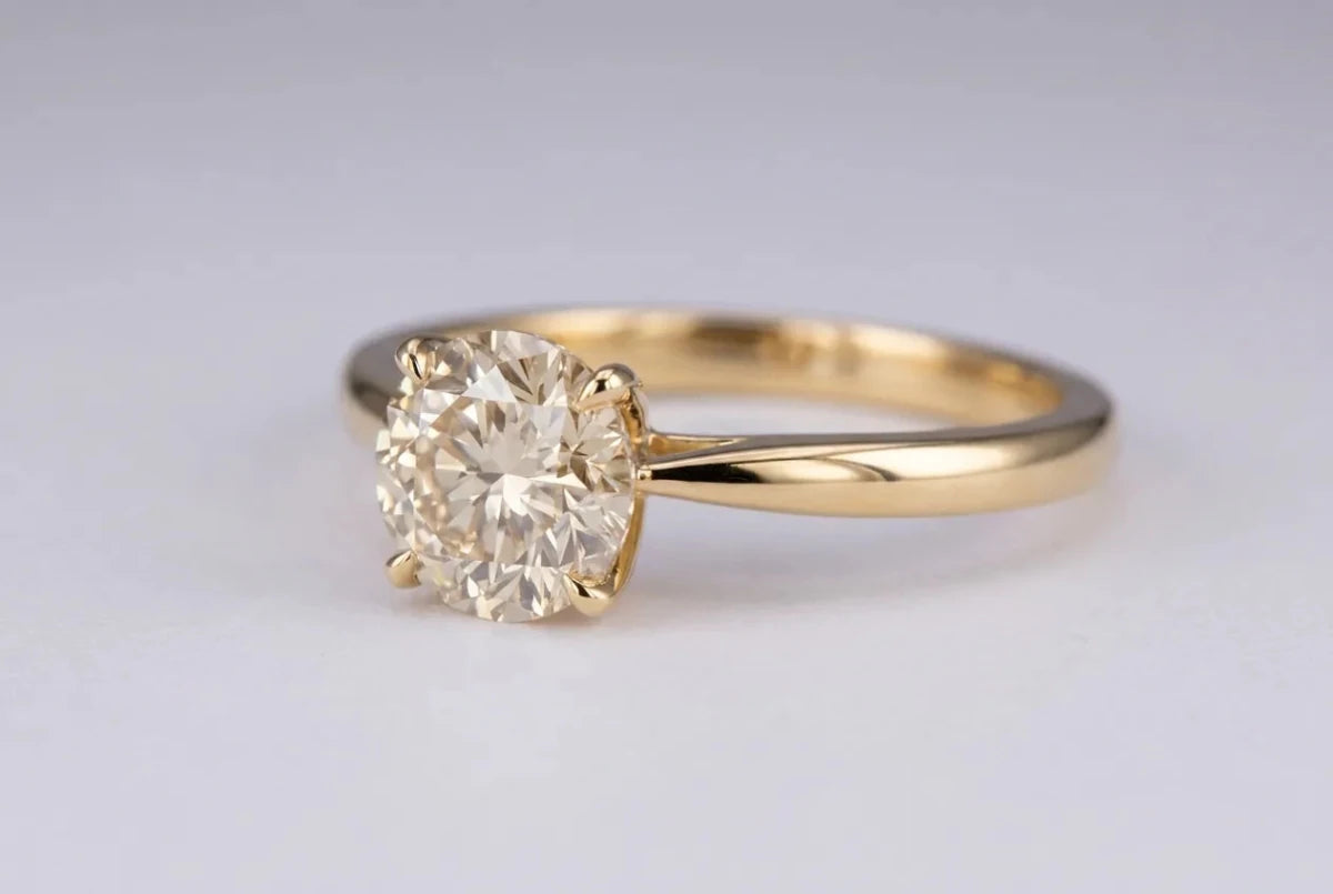 A warm-toned diamond set in a yellow gold ring where the warmth blends with the metal