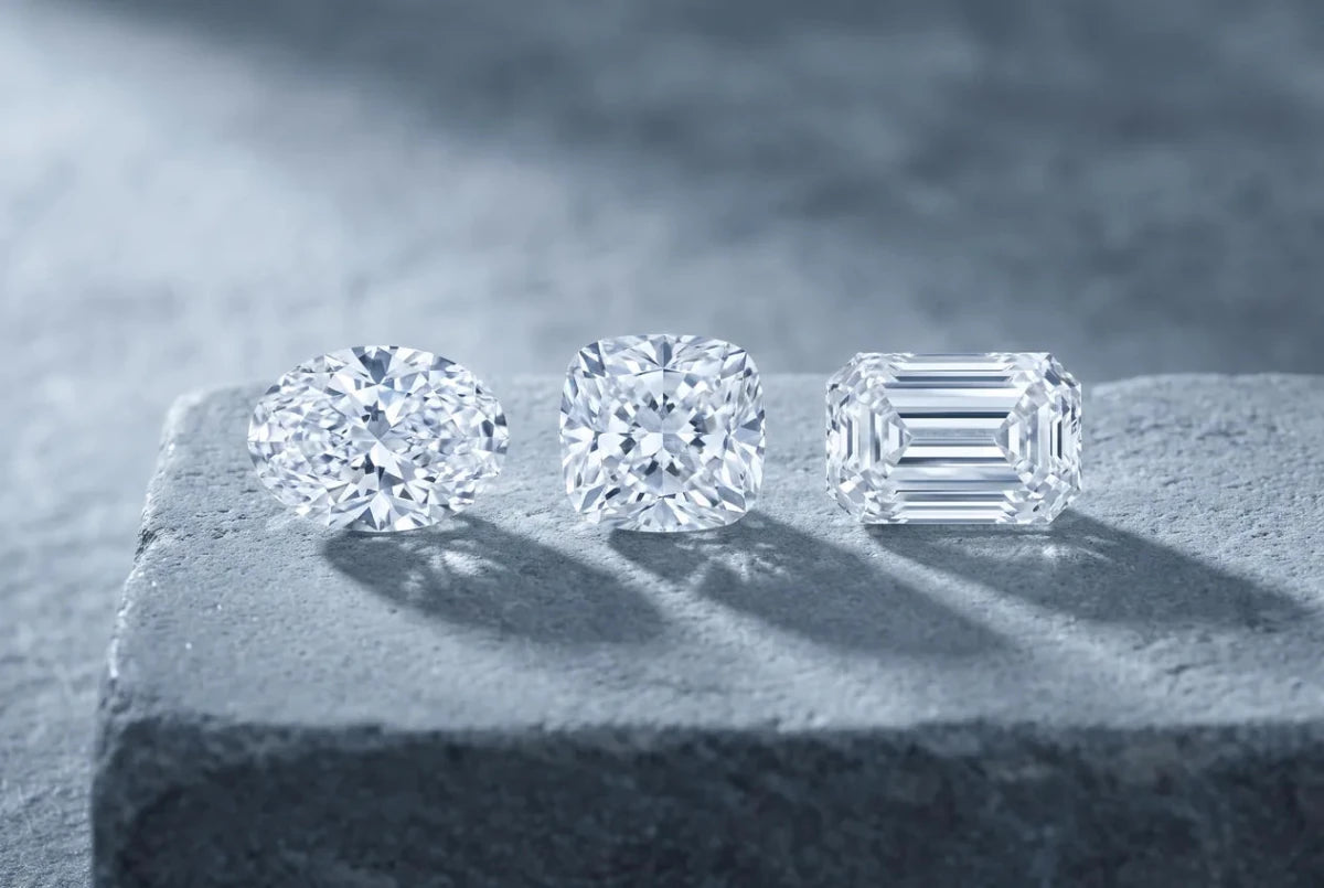An oval, a cushion cut and an emerald cut diamond lying face-up side by side