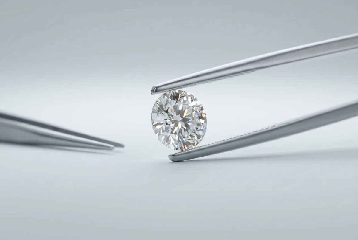 A round brilliant diamond held in steel jeweler's tweezers
