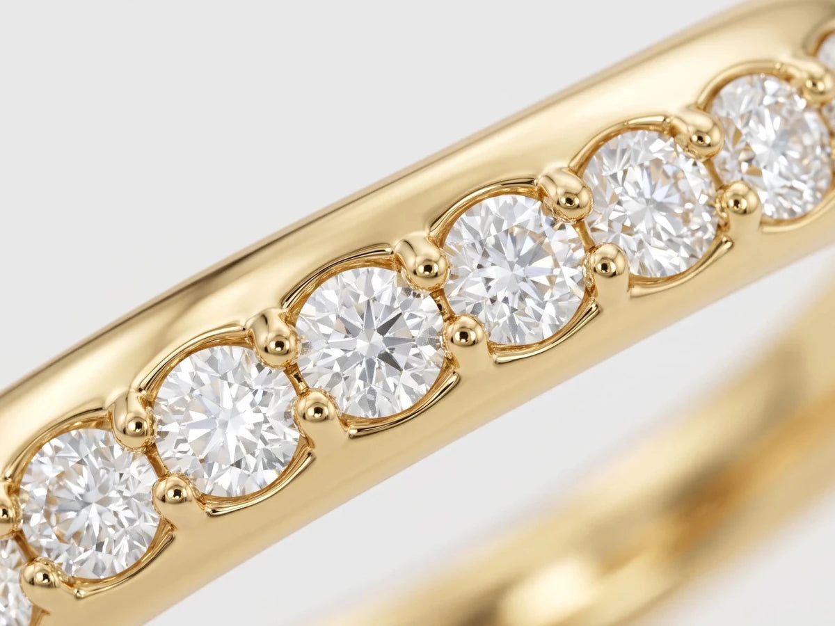 Macro close-up of a polished gold ring shank and the diamonds set into it, filling the frame