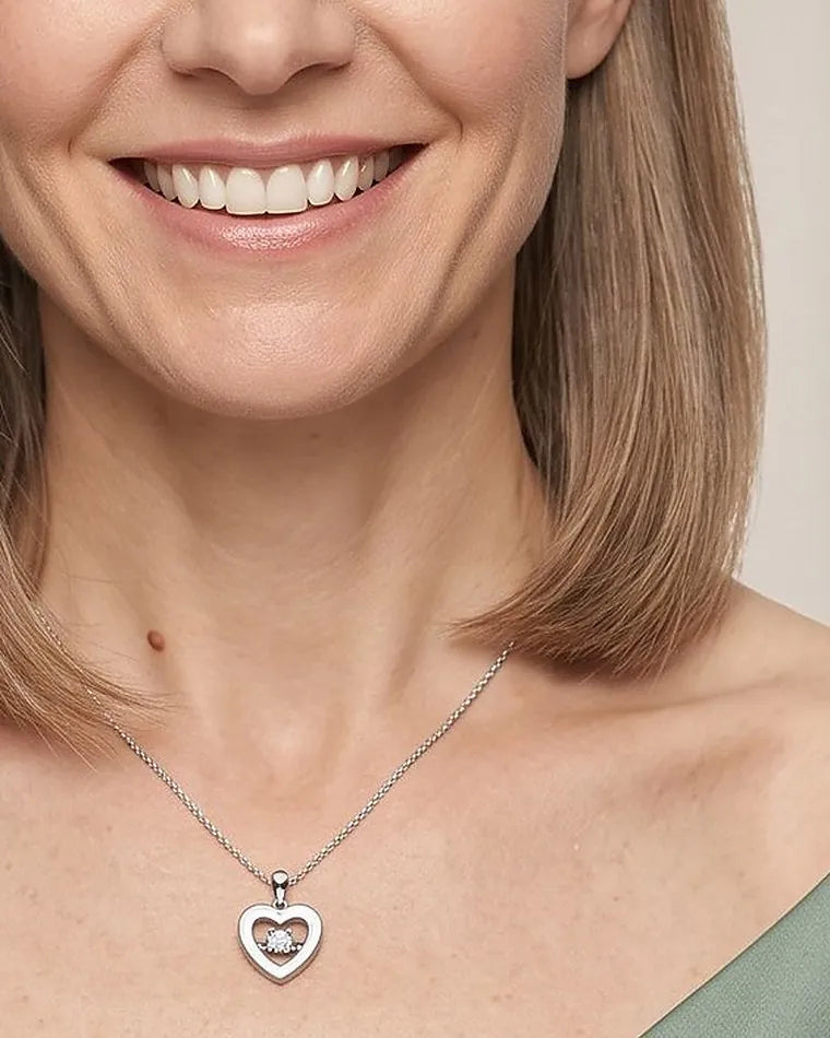A smiling woman in sage green wearing a white gold diamond heart pendant