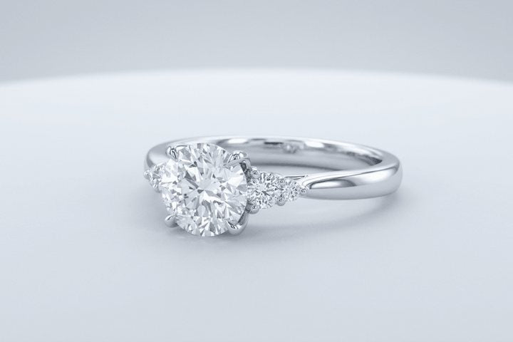 A white gold engagement ring with a round center stone