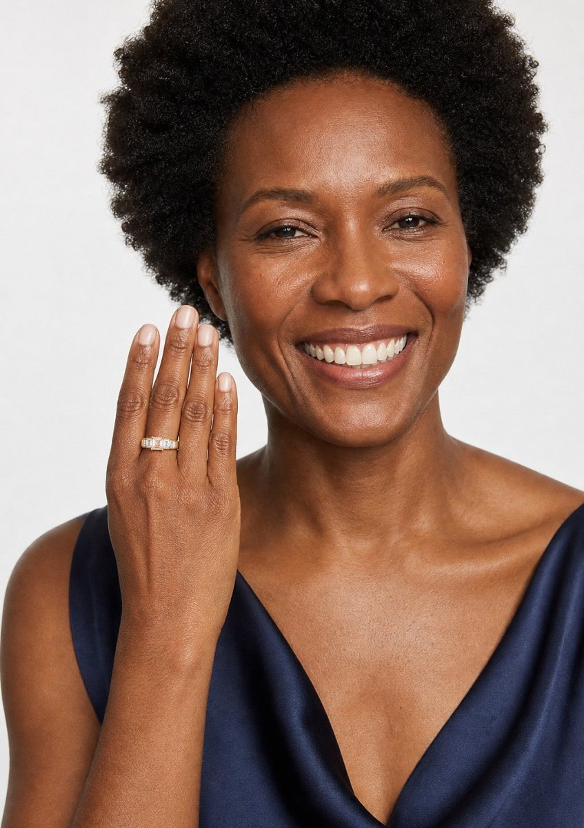 A smiling woman wearing a yellow gold emerald cut diamond ring