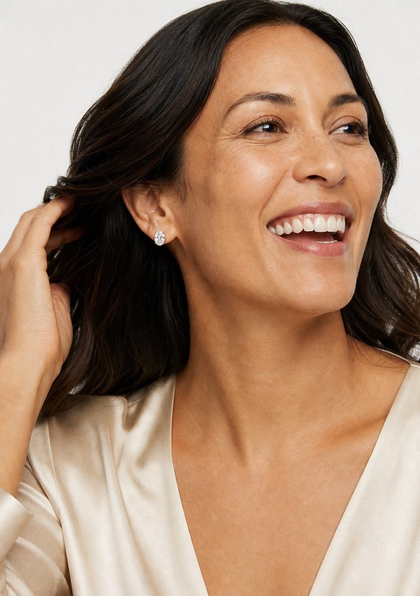 A smiling woman wearing a white gold earrings set with elongated oval diamonds