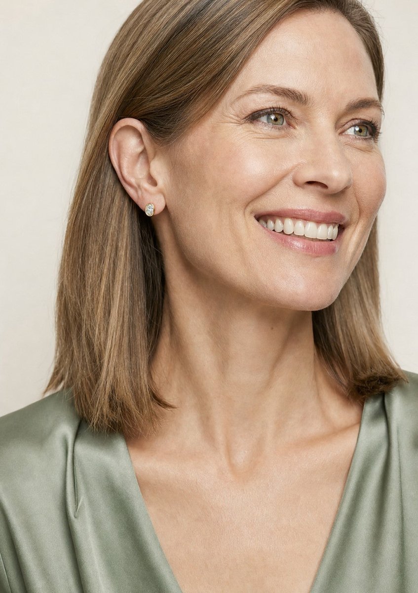 A smiling woman wearing a yellow gold earrings set with elongated oval diamonds