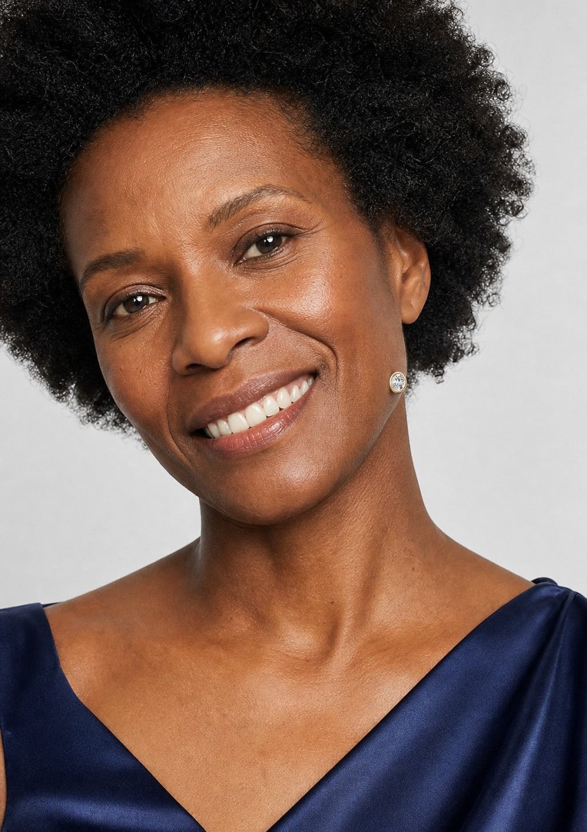 A smiling woman wearing a yellow gold earrings set with elongated oval diamonds