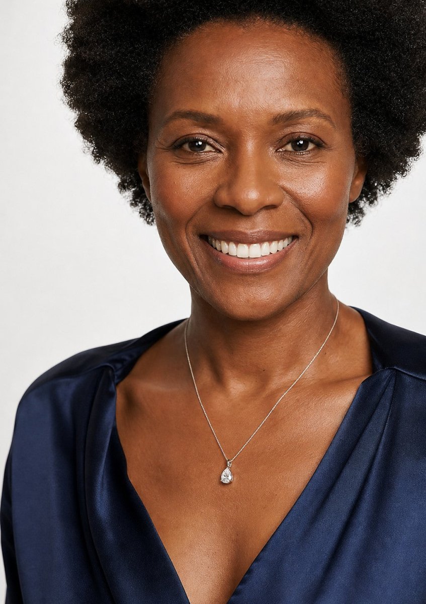 A smiling woman wearing a rose gold pendant set with teardrop shaped pear cut, rounded at one end and pointed at the other diamonds