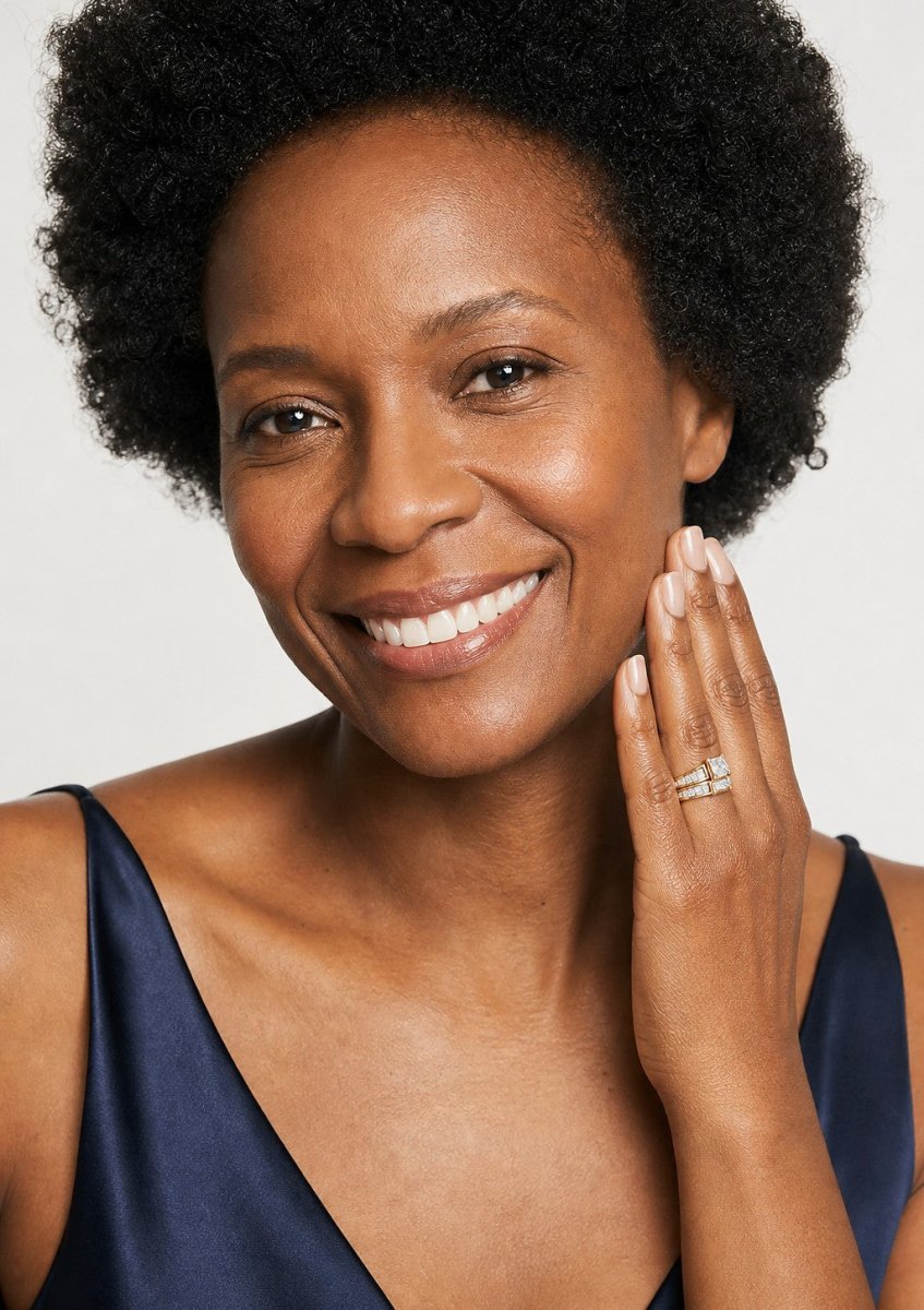 A smiling woman wearing a yellow gold princess cut diamond ring