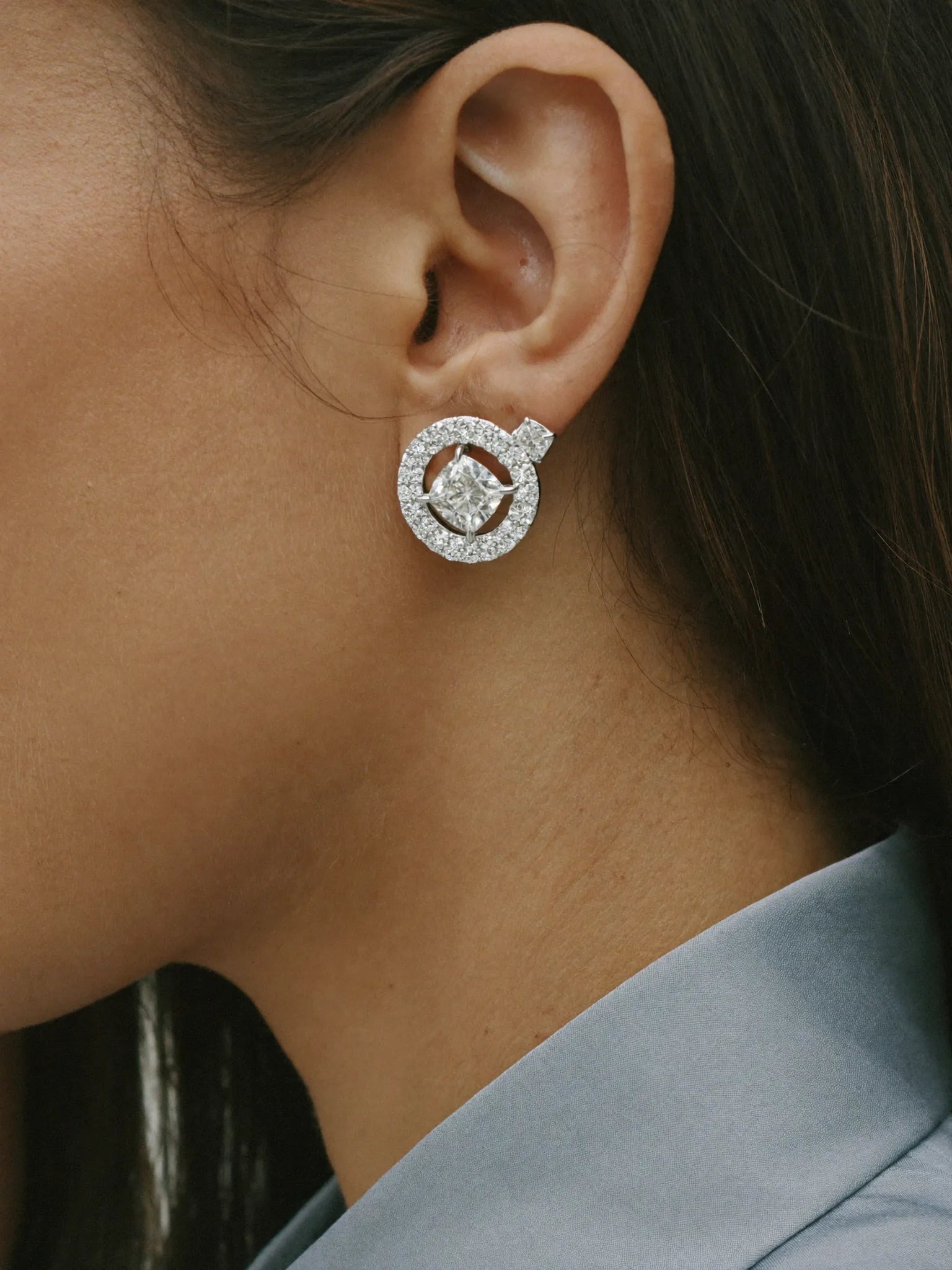 A custom diamond halo stud earring worn on the ear