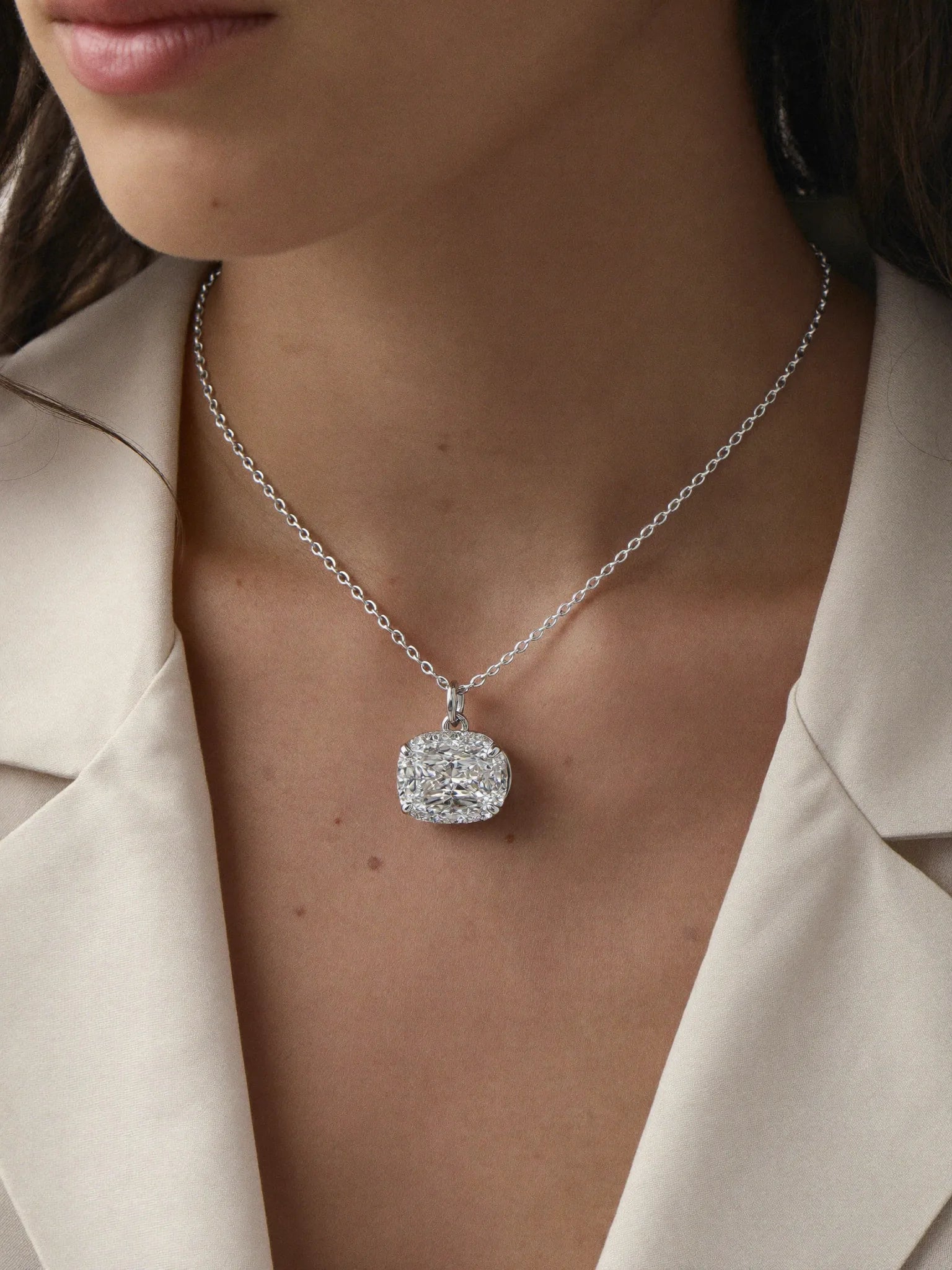 A custom diamond pendant worn at the neckline over a cream silk blouse
